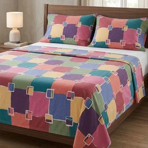 May include: A bed with a wooden frame, featuring a colorful patchwork quilt and two matching pillowcases. The quilt and pillowcases display a pattern of squares in various colors, including pink, blue, yellow, and green. A lamp sits on the nightstand.