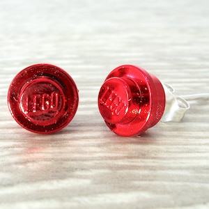 Op de afbeelding: Een paar rode LEGO-steen oorbellen. De oorbellen zijn gemaakt van metaal en hebben een zilveren pin.