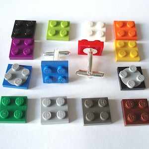 May include: A set of 10 cufflinks featuring LEGO bricks in various colors, including red, blue, green, yellow, black, white, gray, and brown. The cufflinks are made of silver and feature a LEGO brick design.