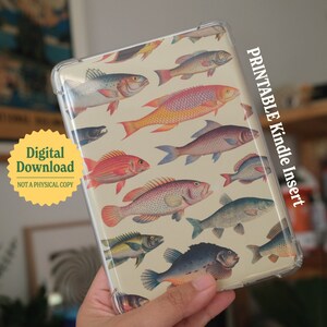 以下が含まれることがあります： カラフルな魚のプリントデザインが施された透明なプラスチックケース。ケースはKindle電子書籍リーダー用です。ケースの側面には「Printable Kindle Insert」というテキストが印刷されています。