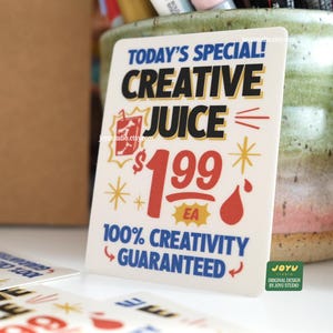 May include: A white rectangular sign with the text "TODAY'S SPECIAL! CREATIVE JUICE $1.99 EA 100% CREATIVITY GUARANTEED" in blue, red, and yellow. The sign has a cartoon-style design with a drink and starbursts.