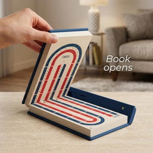 May include: An open, book-shaped game board in blue and white, displaying a red and blue track design. The word "FINISH" is visible. The text "Book opens" is also present.