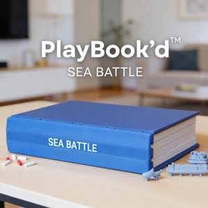 Puede incluir: Un juego PlayBook'd Sea Battle azul sobre una mesa de madera clara. El juego incluye una funda azul con forma de libro, barcos grises en miniatura y piezas de juego rojas y blancas. El texto "PlayBook'd" y "SEA BATTLE" son visibles.