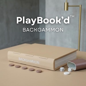 Puede incluir: Un juego de backgammon beige con el texto "PlayBook'd" y "BACKGAMMON" en la portada. El juego incluye fichas marrones, dados y un cubilete. El juego se muestra sobre una superficie beige.