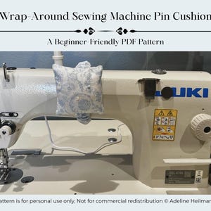 May include: A white sewing machine with a blue and white floral pin cushion attached. The text "Wrap-Around Sewing Machine Pin Cushion" and "A Beginner-Friendly PDF Pattern" are at the top. The sewing machine has the brand name "JUKI" on it.