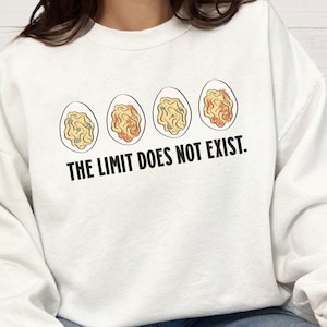 May include: White sweatshirt with a graphic of four deviled eggs and the text "THE LIMIT DOES NOT EXIST." The eggs have yellow and orange fillings. The sweatshirt is a casual, comfortable style.