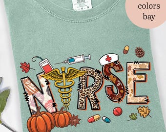May include: A light green Comfort Colors t-shirt with the word "NURSE" in a fall-themed design. The design includes pumpkins, leaves, a caduceus, a syringe, and a nurse's hat.