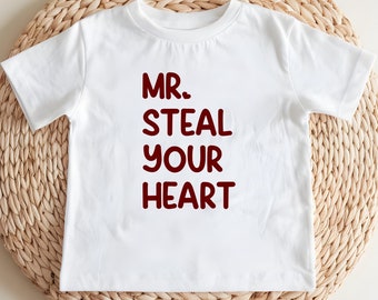 May include: White t-shirt with the text "MR. STEAL YOUR HEART" printed in red.