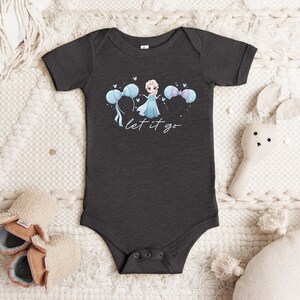 K&ouml;nnte beinhalten: Dunkelgrauer Baby-Body mit einer Cartoon-Prinzessin in blauem Kleid und blauen Luftballons. Der Text "let it go" steht in Schreibschrift darunter. Der Body hat kurze &Auml;rmel und Druckkn&ouml;pfe. Babybekleidung.
