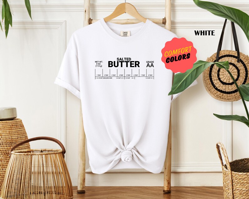 May include: White t-shirt with the text "Salted Butter" and a nutrition label graphic. The text "Comfort Colors" is on a pink circle.