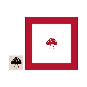 May include: A red and white mushroom with white dots is inside a red square frame. The mushroom is on a white background.