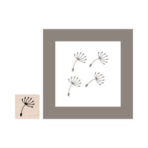 May include: A square image featuring four stylized dandelion seed heads in a light brown color against a white background, framed by a gray border. A small wooden stamp with a single dandelion seed head is in the lower left corner.