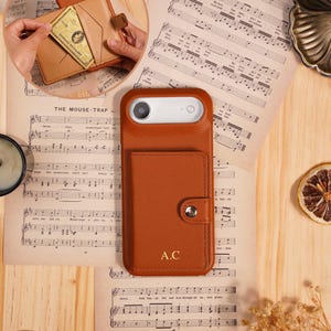 Gepersonaliseerd iPhone-hoesje met reliëflederen initialen, kaartvakje en make-upspiegel, ideaal als cadeau voor vrienden.