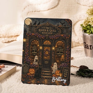 May include: A rectangular sign featuring an illustration of The Raven & Quill Bookshop with a black cat, two ghosts, pumpkins, and autumn leaves. The text reads The Raven & Quill Bookshop, Books Spells & Stories, Rare Books Old Magic & Curiosities, Open, Here Lies A Good Book Well Loved Never Lost, Read If You Dare, and Brittney.