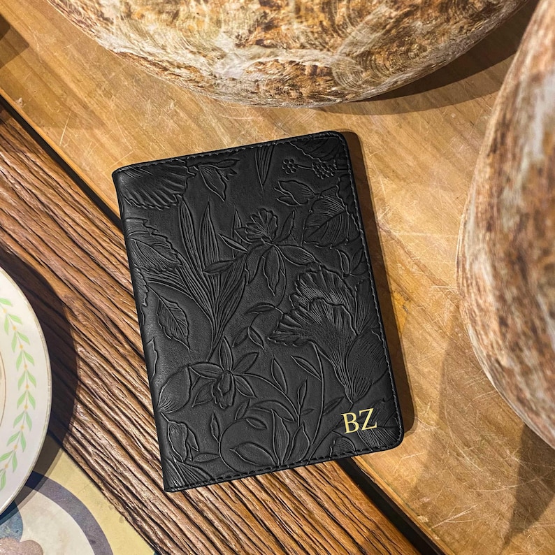 May include: Black leather passport holder with a floral embossed design and the initials "BZ" in gold lettering.