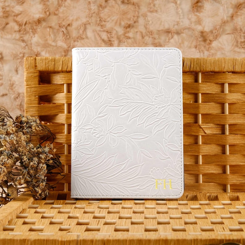 May include: White leather journal with a floral embossed design and the initials "FH" in gold lettering.