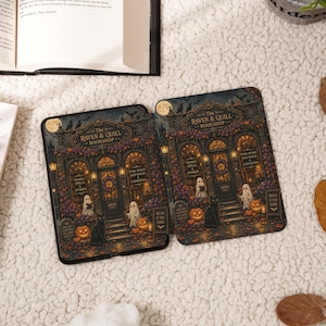 May include: Two e-readers displaying a graphic of The Raven & Quill Bookshop, featuring ghosts, a black cat, pumpkins, and autumn foliage. The shop front has signs reading Books Spells & Stories and Rare Books Old Magic & Curiosities.