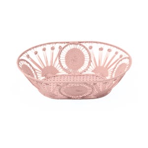 May include: A light pink, open-weave basket with a circular design. The basket is made of woven material and features a series of sunburst-like patterns around the rim. The basket is oval-shaped and sits on a white background.