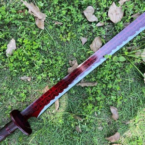 Peut inclure: Une &eacute;p&eacute;e avec une lame rouge fonc&eacute; orn&eacute;e d'un motif g&eacute;om&eacute;trique r&eacute;p&eacute;titif sombre sur toute sa longueur. La lame pr&eacute;sente un bord dentel&eacute; et une finition m&eacute;tallique. Une garde circulaire rouge fonc&eacute; relie la lame &agrave; un manche cylindrique textur&eacute;.