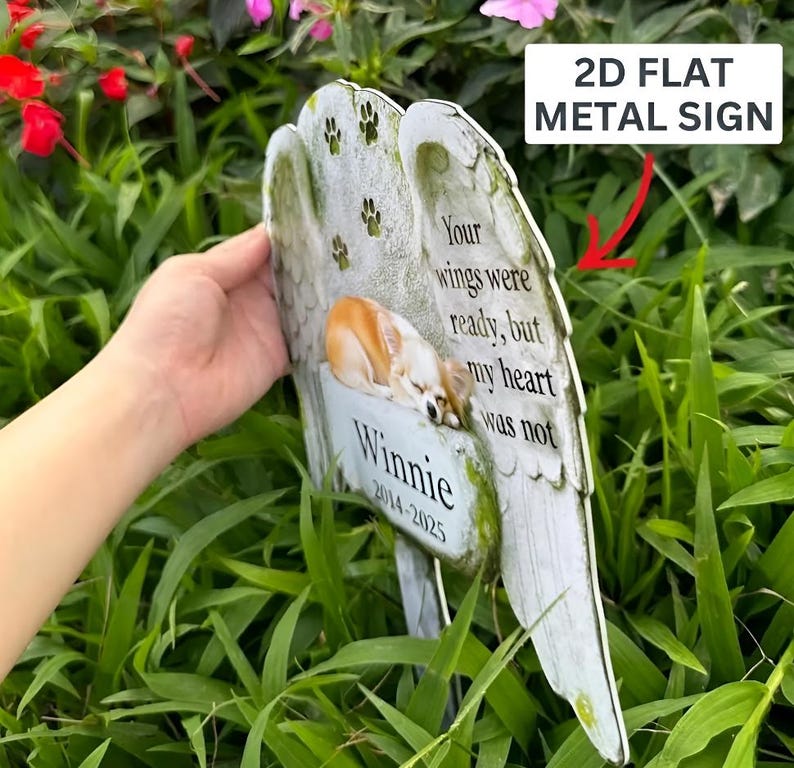 May include: A 2D flat metal sign shaped like angel wings with a printed image of a sleeping dog. The text reads: Your wings were ready, but my heart was not, Winnie, 2014-2025. The sign features small paw print graphics and a weathered stone texture.