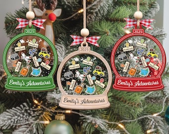 May include: Three Christmas ornaments shaped like snow globes, each with a different colored frame: green, natural wood, and red. Each globe features travel-themed icons and the text "Emily's Adventures" and "2025".