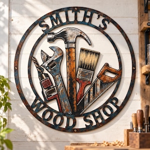 May include: A circular metal wall sign with a distressed, rusted finish featuring the text SMITH'S WOOD SHOP. The design includes a central hammer, an adjustable wrench, a paintbrush, a hand saw, and a drill, all arranged within the circular frame.