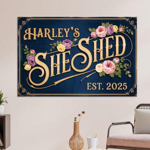 May include: A navy blue sign with gold lettering that reads "Harley's She Shed" with the establishment year "EST. 2025". The sign is decorated with floral accents in pink, purple, and yellow.