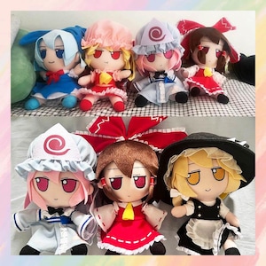 May include: A collection of plush dolls featuring anime-style characters. The dolls have large eyes, colorful outfits, and various hairstyles. The dolls are in shades of blue, pink, red, and black. Some dolls wear hats and bows.