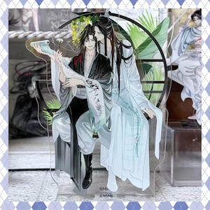 Peut inclure: Support en acrylique représentant deux personnages de style anime en robes fluides. L'un porte du noir et gris, l'autre du blanc. Ils sont assis, l'un tenant un parchemin. Le fond comprend une roue décorative et du feuillage. Le support a une bordure à motifs bleus et blancs.