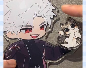Könnte beinhalten: Ein klarer Acryl-Anhänger mit einem Cartoon-Anime-Charakter mit weißen Haaren und roten Augen, der eine schwarze Jacke trägt. Daneben ist eine kleine Cartoon-Katze mit grau-weißen Streifen abgebildet.