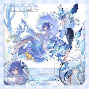May include: A blue and white acrylic standee featuring anime-style illustrations. The standee showcases two female characters with blue hair and outfits, along with two circular pinback buttons. The text "WUTHERING WAVES" and Chinese characters are visible.