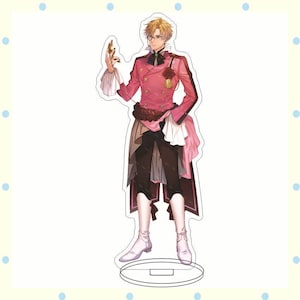 May include: A standing acrylic figure of an anime character in a pink and black outfit. The character has blonde hair, glasses, and is holding a small object. The figure is on a clear base.