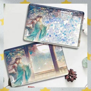 Op de afbeelding: Twee vierkante onderzetters met een romantische anime-stijl illustratie. De kunstwerken tonen figuren in vloeiende teal gewaden, tegen een achtergrond van een maanverlichte hemel en glitter. De onderzetters zijn helder en glanzend.