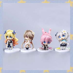 May include: Four small anime-style figurines. The figurines have large eyes and colorful hair. The first has blonde hair and a black and white outfit. The second has brown hair and a white and red outfit. The third has pink hair and a black outfit. The fourth has white hair and a black and blue outfit.