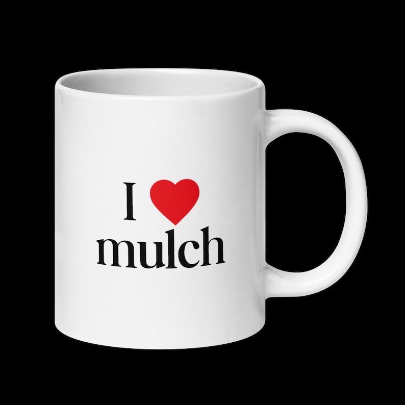 K&ouml;nnte beinhalten: Wei&szlig;e Keramiktasse mit einem roten Herzen und dem Text "Ich liebe Mulch" in Schwarz.
