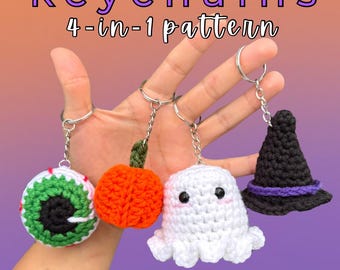 Puede incluir: Se muestran cuatro llaveros de ganchillo con temática de Halloween: un ojo, una calabaza, un fantasma y un sombrero de bruja. Los llaveros están en anillos plateados. El texto "HALLOWEEN keychains 4-in-1 pattern" está en la parte superior.