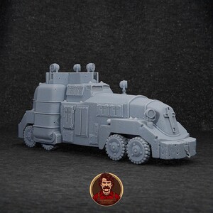 May include: A grey, detailed model of a heavily armoured vehicle with a cross on the side. The vehicle has a large, boxy body with a raised cab and a long, narrow front end. The model is made of plastic and is painted in a matt grey finish.