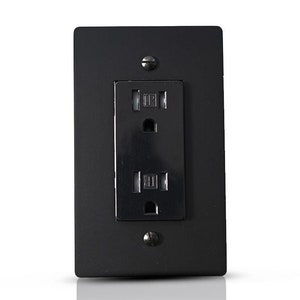May include: A black electrical outlet with two slots and a ground prong. The outlet is mounted on a black wall plate.