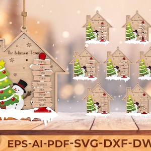 May include: Wooden Christmas ornament in the shape of a house, featuring a snowman, Christmas tree, and family names. The ornament has a natural wood finish and includes the text "The Johnson Family".