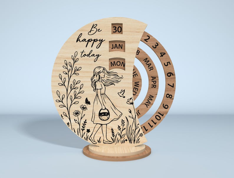 Puede incluir: Calendario perpetuo de madera con un dise&ntilde;o cortado con l&aacute;ser. El calendario presenta a una mujer caminando por un campo, las palabras "Be happy today" y anillos giratorios para la fecha, el mes y el d&iacute;a. El calendario es de madera clara.