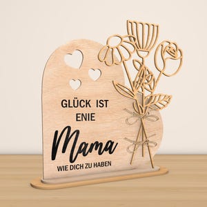 May include: Wooden sign with a heart shape and a bouquet of flowers. The sign reads "Gl&uuml;ck ist eine Mama wie dich zu haben" which translates to "Happiness is having a mom like you".