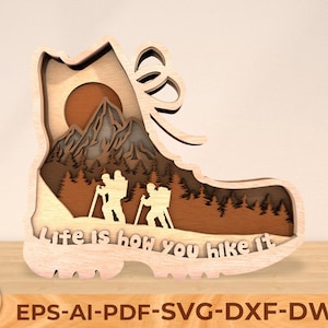 May include: A wooden cutout of a hiking boot with a mountain scene and the text "Life is how you hike it".