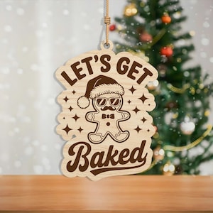 May include: Wooden Christmas ornament featuring a gingerbread man wearing sunglasses and a Santa hat. The text "LET'S GET BAKED" is above and below the gingerbread man. The ornament is hanging by a natural twine string.