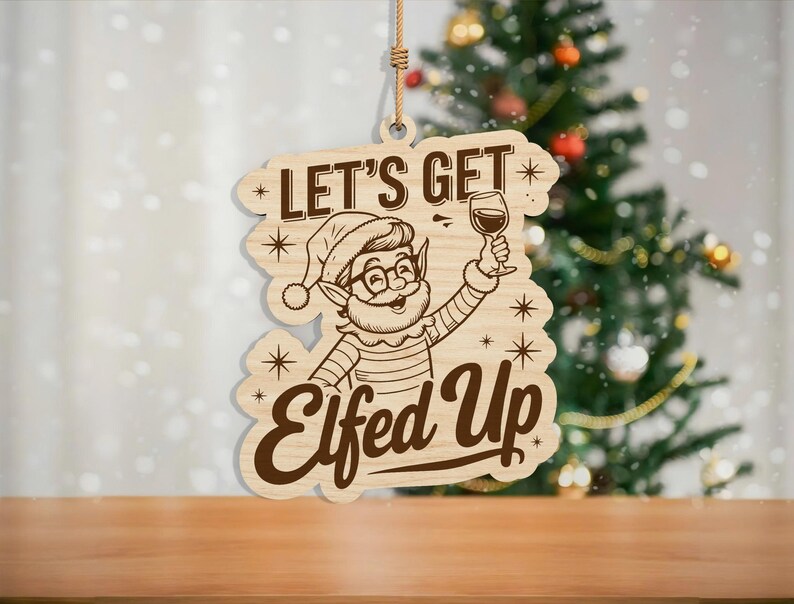 May include: Wooden Christmas ornament with the phrase "Let's Get Elfed Up" and a cartoon elf holding a wine glass. The ornament is light brown with dark brown text and design elements. A festive holiday decoration.