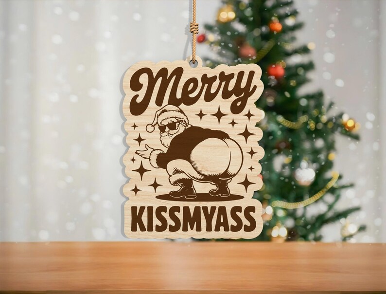 May include: Wooden Christmas ornament with a Santa Claus design. The ornament features the text "Merry" above an illustration of Santa squatting, with the text "Kiss My Ass" below. The ornament is hanging by a natural fiber string.