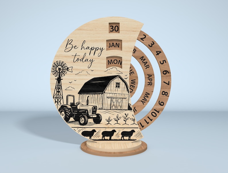 Puede incluir: Calendario perpetuo de madera con una escena de granja, que incluye un tractor, un granero y ovejas. El calendario muestra la fecha, el mes y el d&iacute;a, con las palabras "Be happy today" grabadas en la parte delantera. La base es redonda.