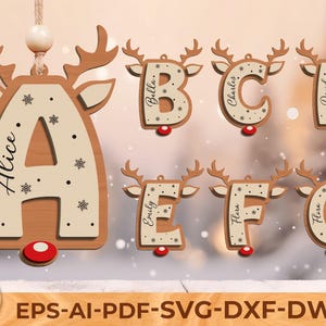Könnte beinhalten: Weihnachtsschmuck aus Holz in Form von Rentieren, jeweils mit einem Buchstaben und einem Namen. Die Buchstaben A bis G sind abgebildet, mit Namen wie Alice, Bella, Charles und David. Jeder Schmuck hat einen roten Knopf unten.