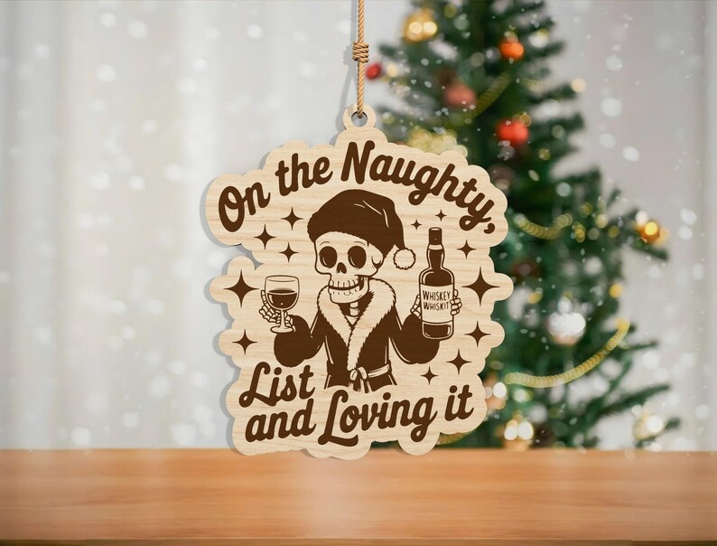May include: Wooden Christmas ornament with a skeleton wearing a Santa hat and holding a glass of wine and a whiskey bottle. The text reads "On the Naughty List and Loving it". The ornament is hanging by a natural twine.