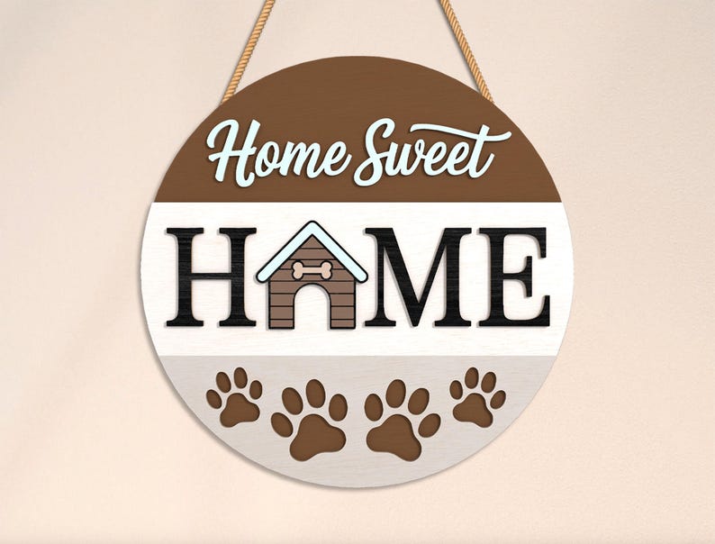 May include: A round wooden sign with the words "Home Sweet HOME" in white and black. The sign features a dog house graphic and paw prints, with a brown and white color scheme, and a rope for hanging.