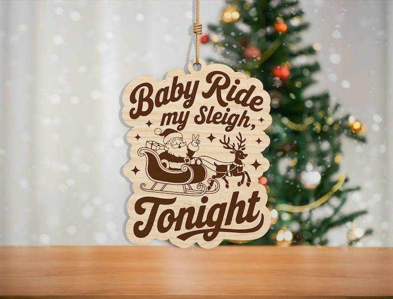 May include: Wooden Christmas ornament with the text "Baby Ride my Sleigh, Tonight". The ornament features a Santa Claus in a sleigh pulled by reindeer. The ornament is hanging in front of a Christmas tree.